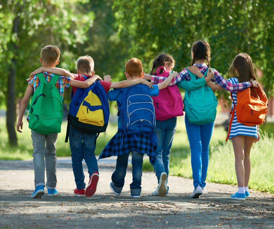 School kids walking home from school together wearing bbackpacks